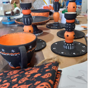 decoração de halloween, uma mesa com candelabros e xícaras cores laranja preta com desenhos de luas, estrelas e teias de aranha