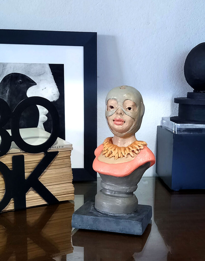 estatueta busto feminino aviadora vintage em estante com outros objetos decorativos