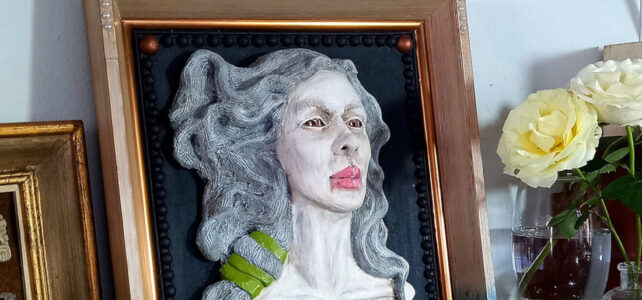 Relevo autoral Vento de Afrodite em cerâmica fixado em moldura decorando uma prateleira larga com outros elementos decorativos