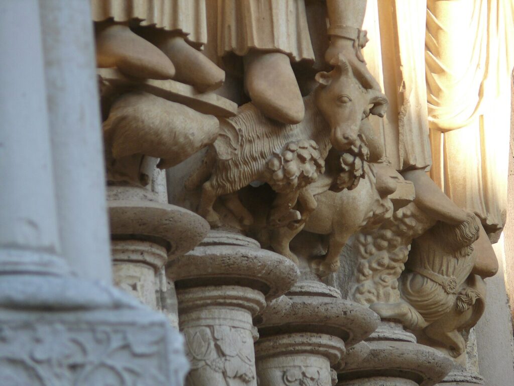 Detalhe da base das colunas onde os profetas estão apoiados no pórtico da Catedral de Chartres. Mostra pequenas figuras e animais esculpidos sob os pés das estátuas principais.