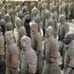 Estátuas de guerreiros de terracota com partes com pigmentos originais preservados em tons de vermelho, rosa e verde nas vestimentas.