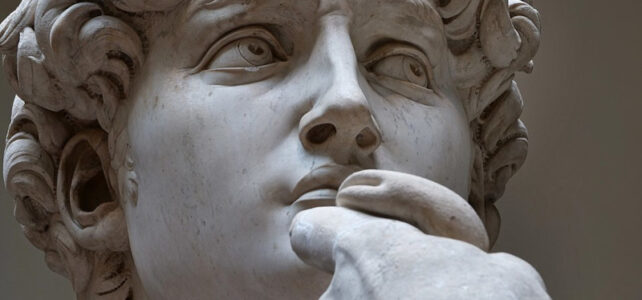 Close-up do rosto da estátua David de Michelangelo focado na expressão intensa e decidida do olhar direcionado para o lado