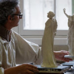 Técnico olhando duas esculturas de dançarina para produzir figuras em porcelana na Manufatura de Sèvres
