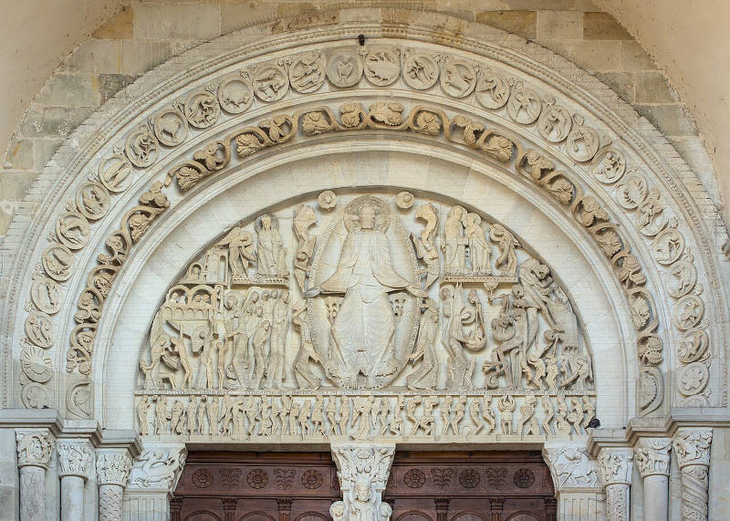 foto de portal de uma catedral medieval destacando a grande quantidade de relevos de pequenas esculturas ao redor de um grande figura de cristo esculpidos na pedra