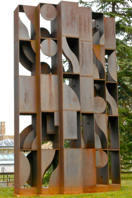 escultura pública geométrica de metal marrom em uma praça
