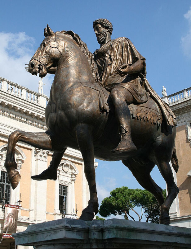 estátua em tamanho natural em bronze escuro de um homem com roupas romanas sobre um cavalo, colocada em uma praça