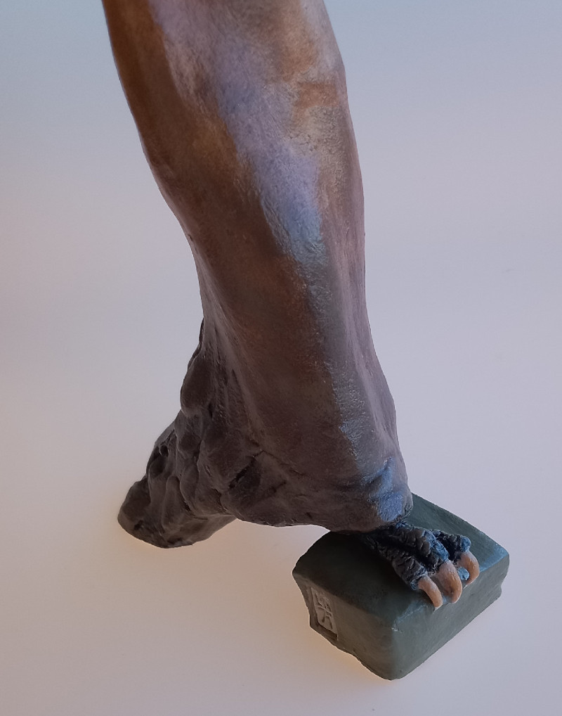 detalhe de uma escultura em cerâmica de figura feminina mostrando um pé de ave de rapina aparecendo por baixo do vestido