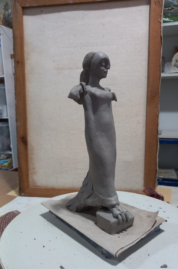 escultura feminina em argila em uma bancada de ateliê