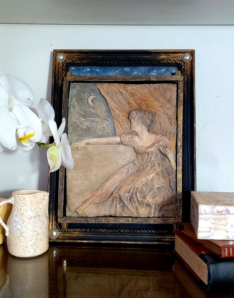 escultura relevo em moldura em aparador decorado com objetos de arte, mulher olhando a lua